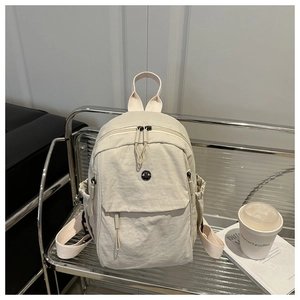 Detail of off-white nylon backpack featuring drawstring side pockets and metal zippers
