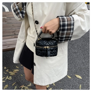 Chic black quilted mini crossbody bag with gold chain strap shown in a city street setting