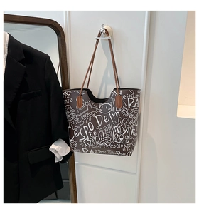 Dettaglio di una borsa tote marrone con graffiti bianchi artistici e manici in pelle