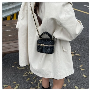 Classic black quilted leather box bag with gold chain strap shown in a street style view