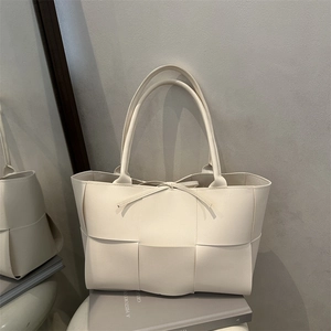 Off-white woven leather tote bag with wide strap design and decorative tie closure