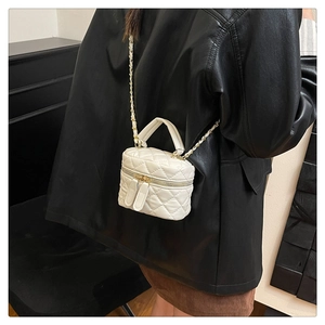 Close-up of a white quilted mini bag with gold chain strap on a black leather jacket