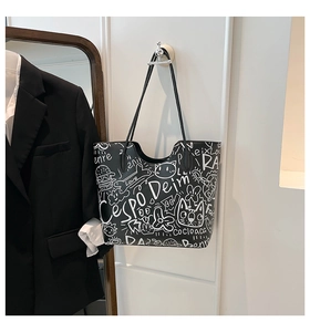 Dettaglio della borsa tote graffiti con stampe di gatti e ossa e tracolle lunghe