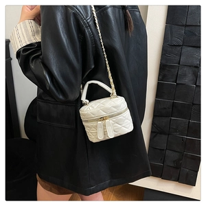 Detailed view of cream quilted mini box bag with chain strap and dual zippers