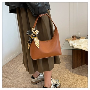 Close-up of brown litchi pattern leather bag featuring a decorative silk scarf on handle