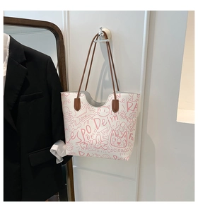 Dettaglio della borsa tote bianca con stampa graffiti rosa e sottili manici marroni