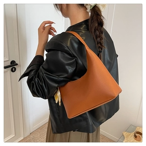 Close-up of caramel faux leather shoulder bag with floral scarf accent on a model