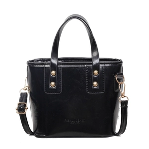 Glossy black leather bucket bag with top handle and golden hardware on white background