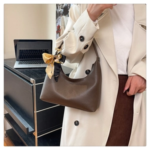 Detail view of a brown lychee-patterned hobo bag styled with a silk scarf on the strap