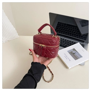 Macro shot of red quilted faux leather handbag with dual zippers and gold chain strap