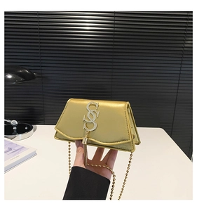 Close-up of golden leather mini bag with decorative S-shaped clasp and metal tassel detail