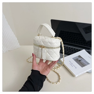 Detail of white quilted crossbody bag featuring dual zippers and gold chain strap