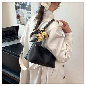 Detail of black lychee grain leather hobo bag with floral silk scarf on a beige coat