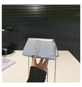 Detail of silver small square bag featuring metallic texture, S-letter logo and tassel