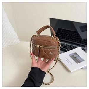 Close-up of brown quilted round bag with gold chain strap and zipper details