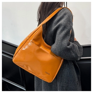 Detail of bright orange tote bag featuring smooth leather texture and Fashion print