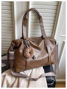 Detail of vintage brown tote bag with woven strap and donut charm against window