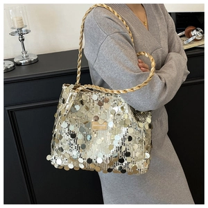 Detailed close-up of shiny sequins on a tote bag with gold woven strap and leather label