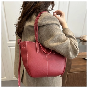 Detail of red pebbled tote bag featuring prominent white contrast stitching and shoulder strap