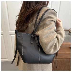 Detail view of black lychee grain leather tote bag featuring contrast white stitching