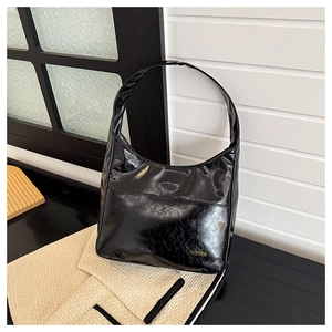 Detail of glossy black hobo bag with gold fashion lettering on knitted fabric
