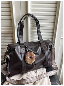 Detail of dark brown tote bag with lychee texture and geometric patterned strap