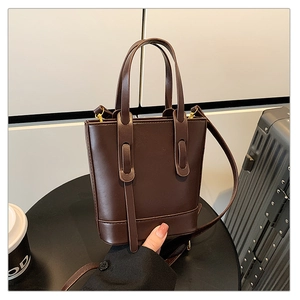 Détail du sac seau en similicuir marron avec ferrures dorées et bandoulière réglable