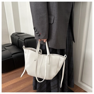 Detailed view of a white tote bag with scalloped edges and decorative leather straps