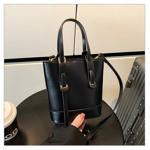 Gros plan d'un sac seau noir avec une finition cuir lisse et des poignées élégantes