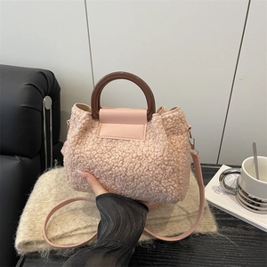 Pink plush leopard print crossbody bag with round handle in a cozy home setting