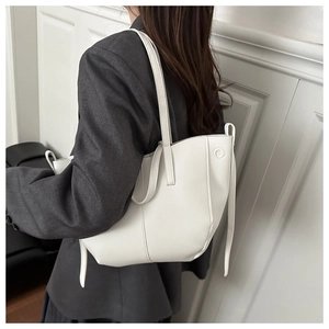 Close-up of white pebble-textured tote bag showing the side metal ring and shoulder strap
