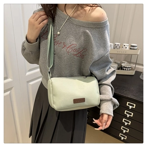 Détail du sac bandoulière en nylon vert menthe avec étiquette et sangle réglable