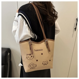 Detail of beige bucket bag with cute cat prints and dark brown adjustable shoulder strap