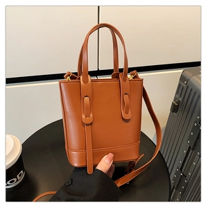 Sac seau en cuir marron avec double poignée et détails dorés dans un cadre lifestyle