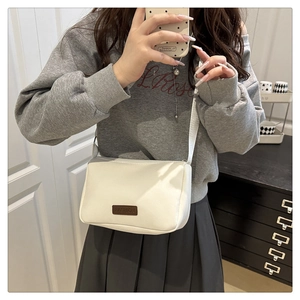 Selfie miroir montrant un sac bandoulière en toile blanche avec logo FASHION en métal