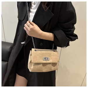 Detail of khaki suede chain bag with rhinestone buckle on black blazer background