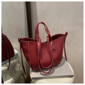 Detail of red lychee grain leather tote bag with white contrast stitching and soft texture
