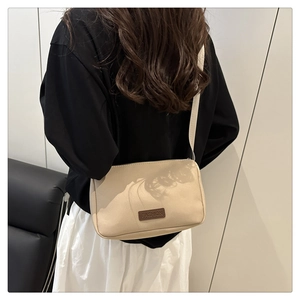 Sac bandoulière tendance en toile beige porté par un mannequin en vue latérale décontractée