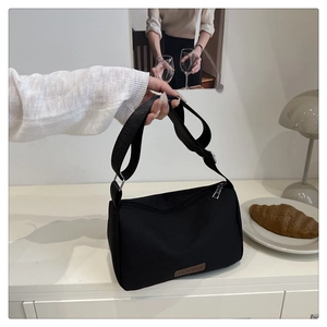 Detail of adjustable strap and leather Fashion patch on black waterproof canvas crossbody bag