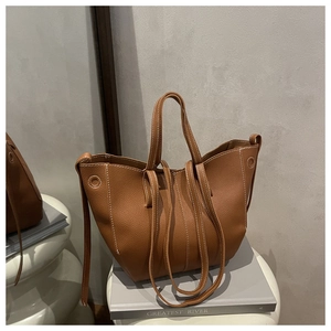 Detail of caramel lychee grain leather tote bag with white contrast stitching and dual straps