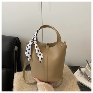 Gros plan du sac seau kaki en cuir grainé avec un foulard décoratif à pois élégant