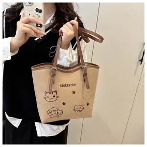 Detail of beige tote bag featuring cartoon cat print and adjustable brown leather handles