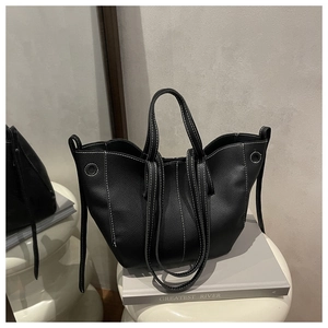 Detail of black pebbled leather tote bag with white contrast stitching on display stand