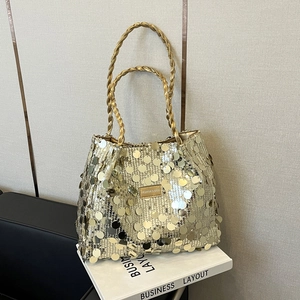 Golden sequin tote bag with woven handles and brand plate on minimalist white background