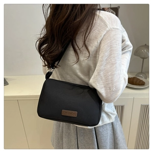 Détail d'un sac bandoulière noir avec étiquette en cuir FASHION et large sangle noire
