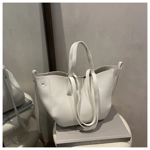 Close-up of a white lychee grain leather tote bag with sturdy handles and a slim shoulder strap