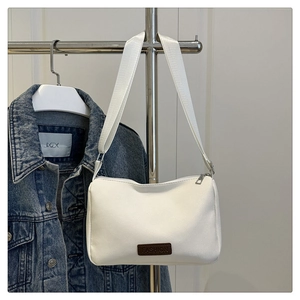 Détail du sac bandoulière en toile blanche avec étiquette en cuir et sangle réglable