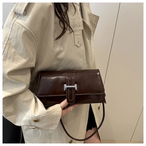 Detail view of dark brown leather handbag featuring a polished silver H-shaped buckle
