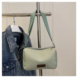 Détail du sac bandoulière en toile vert clair imperméable avec étiquette en cuir