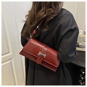 Detail of burgundy underarm bag with silver square buckle and knot strap detail